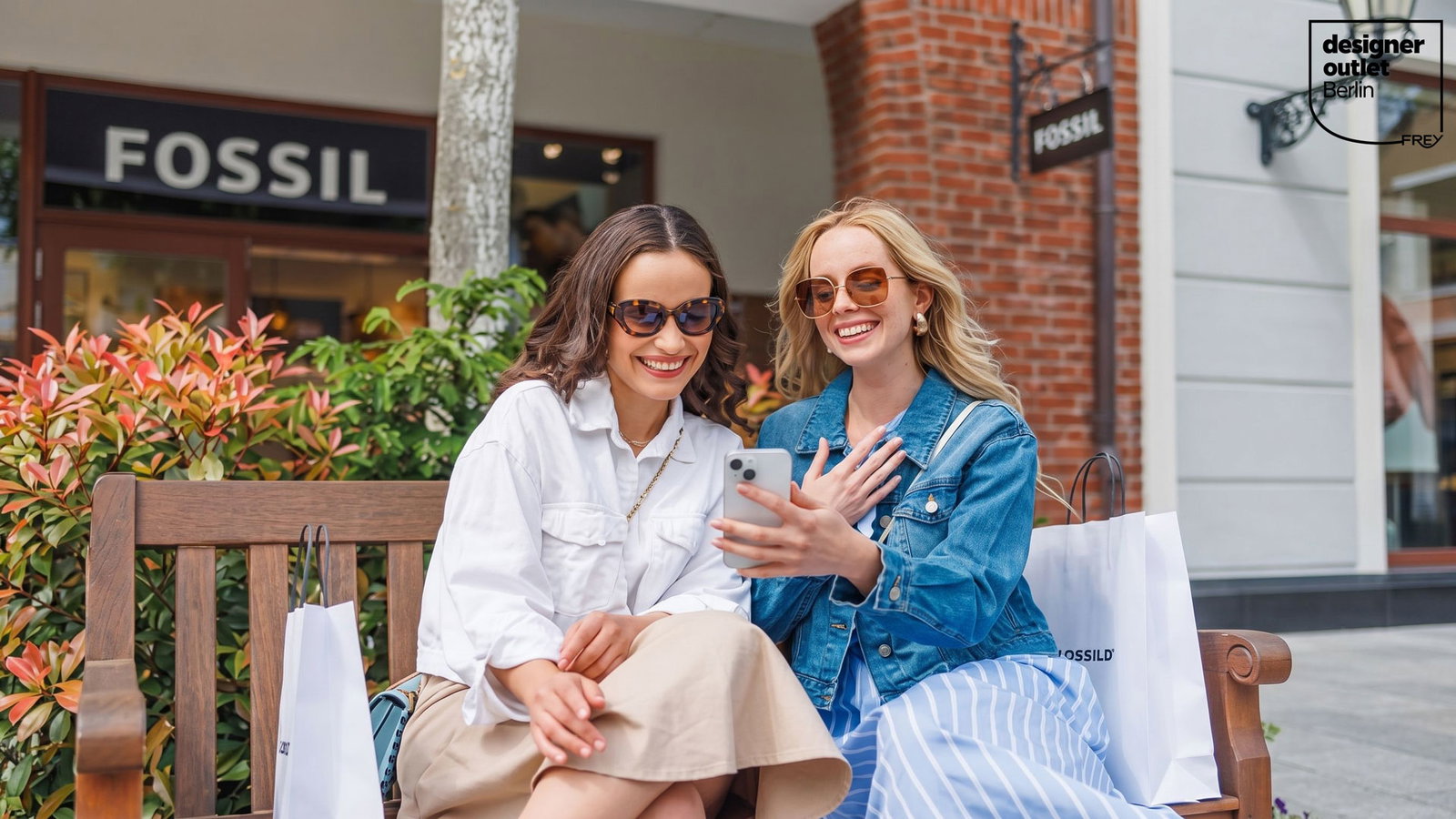 Zwei Frauen sitzen auf einer Bank und schauen auf ein Smartphone