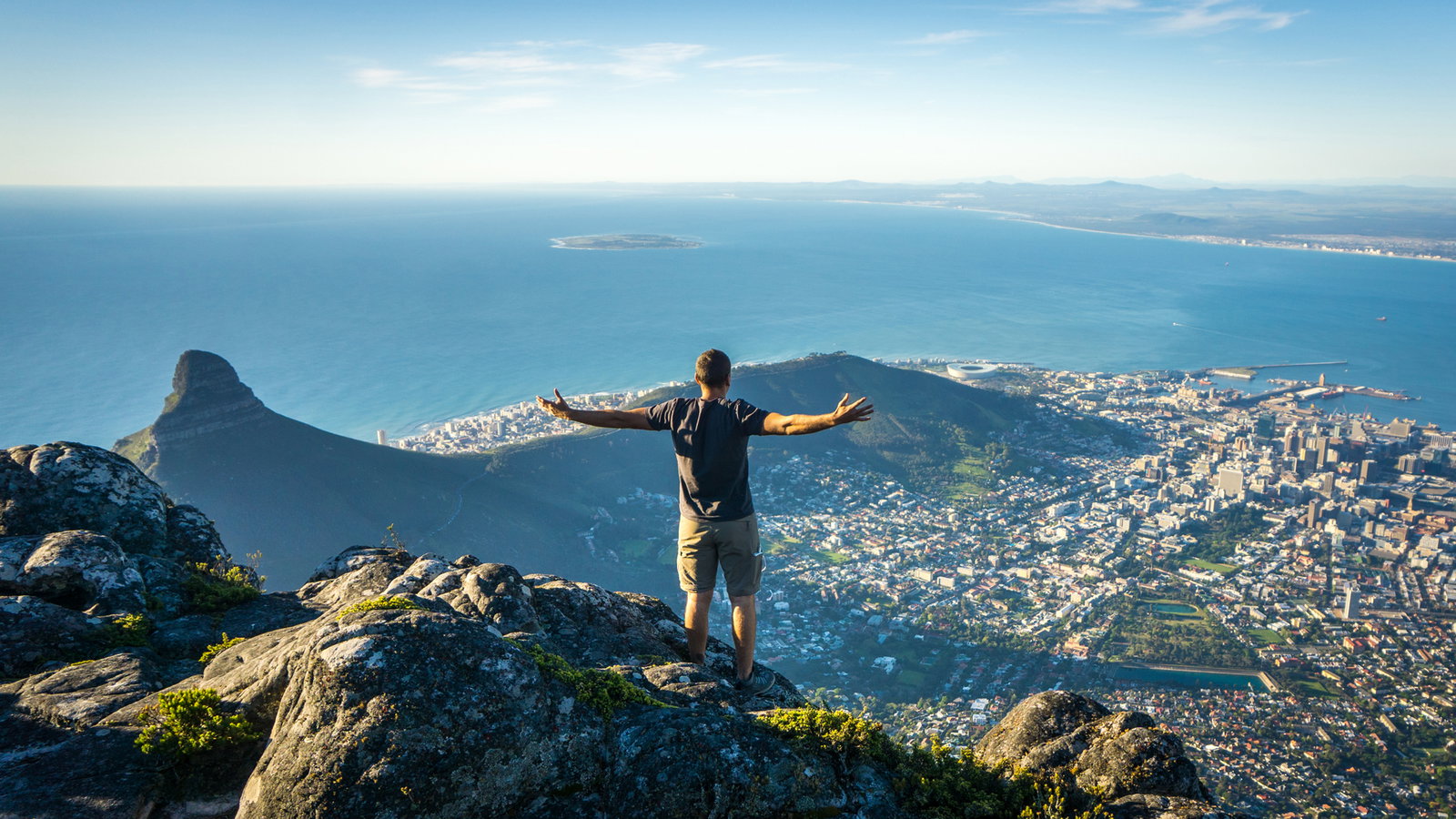 Mann auf einem Berg schaut runter auf eine Stadt